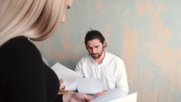 Young woman office worker close up work with papers and her male collegue at the background — Stock Video