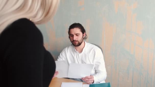 Young woman office worker close up work with papers and her male collegue at the background — Stock Video