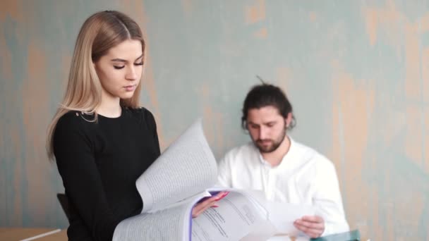 Jeune femme employée de bureau gros plan travail avec des papiers et sa collegue masculine à l'arrière-plan — Video