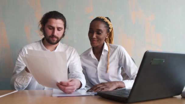 Mulher de negócios africana bonita e homem caucasiano trabalhando em conjunto com laptops — Vídeo de Stock