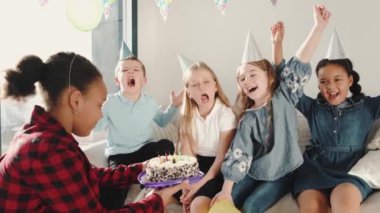 Bir grup çocuk dekore edilmiş evde doğum günü partisi veriyor.
