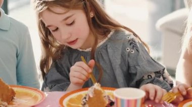 Doğum günü partisinde komik süslerle yemek yiyen bir grup çocuk.