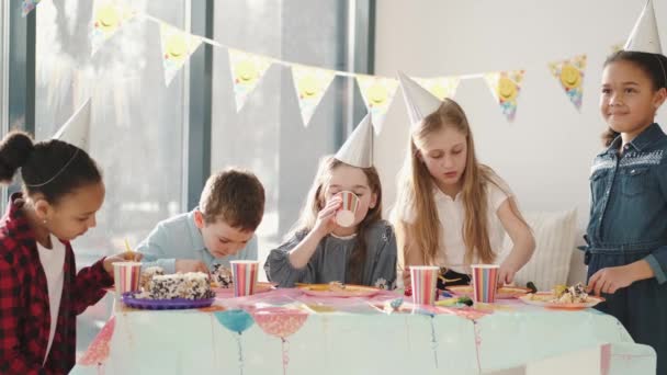 Groupe d'enfants mangeant à la fête d'anniversaire dans des décorations drôles — Video