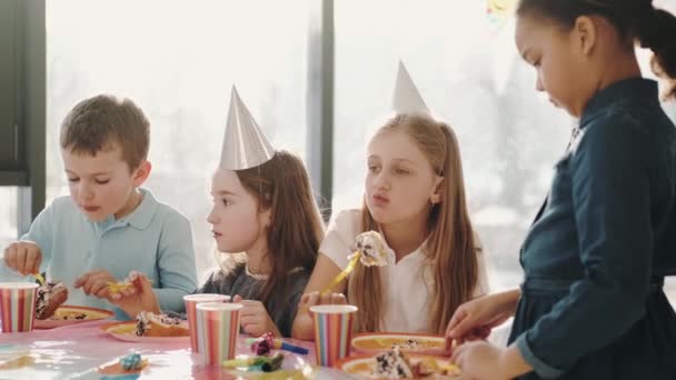 Groupe d'enfants mangeant à la fête d'anniversaire dans des décorations drôles — Video