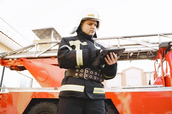 Bombero masculino con tableta en uniforme en el fondo del coche —  Fotos de Stock