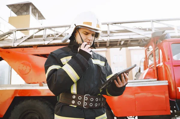 Bombero masculino con tableta en uniforme en el fondo del coche —  Fotos de Stock