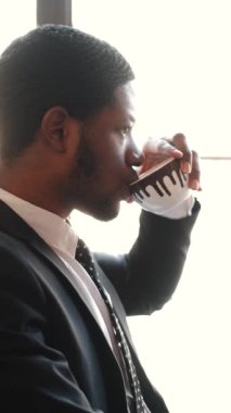 İş adamı kafede dizüstü bilgisayar kullanırken kahve içiyor.