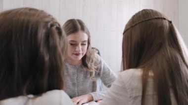 Öğretmen sınıfta iki kız öğrenciye ders veriyor.