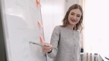 Öğretmen sınıfta iki kız öğrenciye ders veriyor.