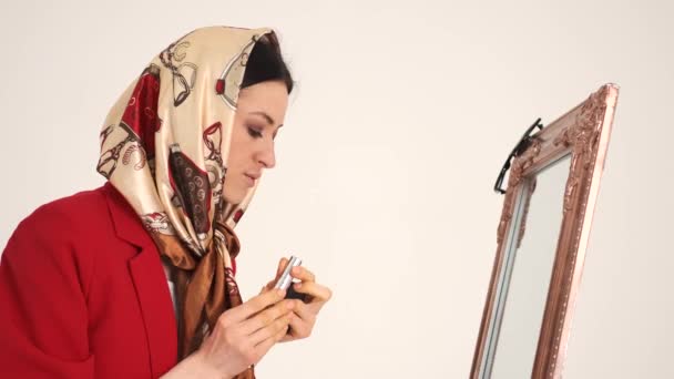 Donna in scialle applicare res rossetto in studio bianco — Video Stock