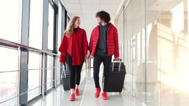 Paar in roter Kleidung mit Koffern auf der Flucht — Stockvideo