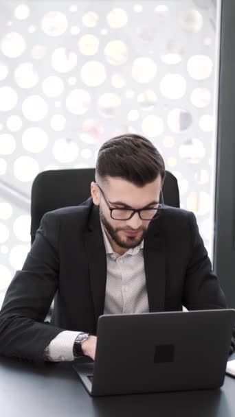 Joven guapo trabajando en el escritorio de la oficina con el ordenador portátil — Vídeos de Stock