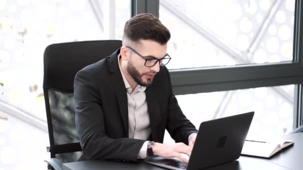 Przystojny młody człowiek pracujący w biurze z laptopem — Wideo stockowe