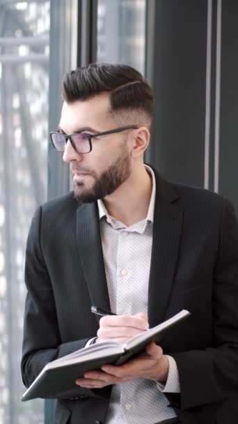 Homme d'affaires mettant des notes debout près de la fenêtre au bureau — Video