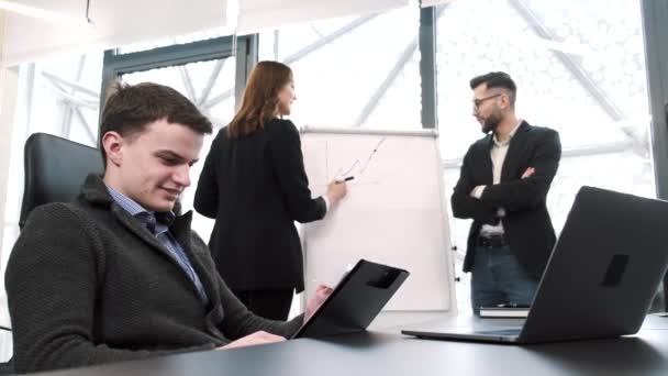 Três colegas de trabalho que trabalham num projecto no escritório — Vídeo de Stock