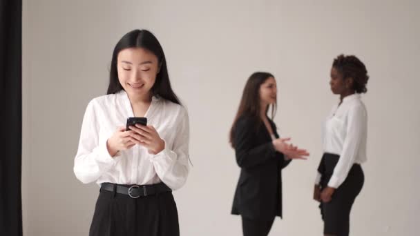 Corean femme en utilisant son smartphone avec des collègues sur fond — Video