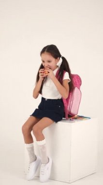 Sırt çantalı neşeli kız stüdyoda oturuyor.