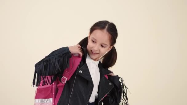 Petite écolière avec sac à dos et uniforme sur le dos blanc — Video