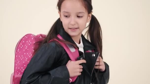 Petite écolière avec sac à dos et uniforme sur le dos blanc — Video