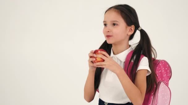 Belle écolière mangeant des pommes isolées en studio — Video
