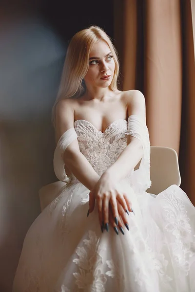 Den vackra unga kvinnan poserar i en bröllopsklänning — Stockfoto