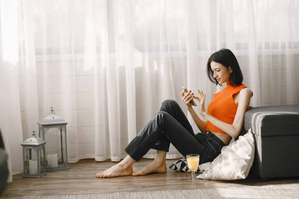 Chica en una chaqueta naranja se sienta en el suelo y bebe jugo — Foto de Stock