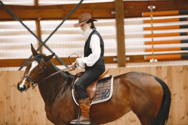 A senior man standing close to a horse outdoors in nature