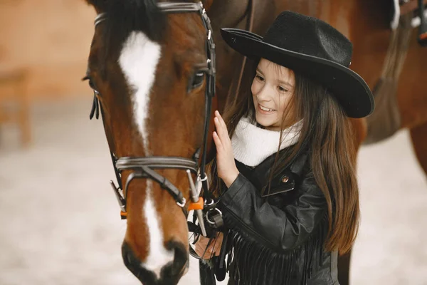 Little girl is riding a horse in a rancho — Stockfoto