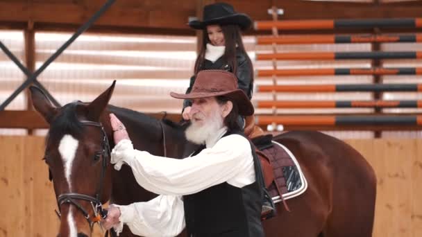 Senior man assisting granddaughter horseback riding in ranch — 비디오