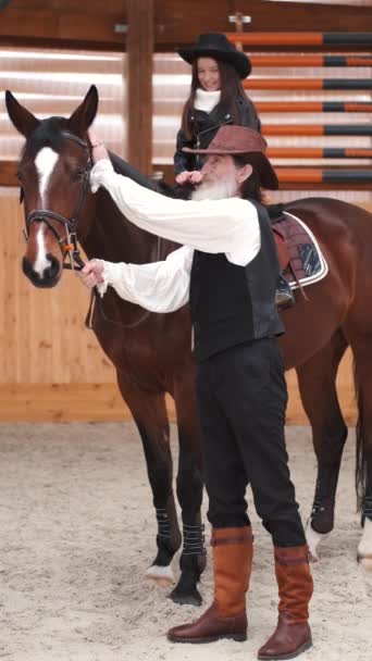 Senior man assisting granddaughter horseback riding in ranch — Stockvideo