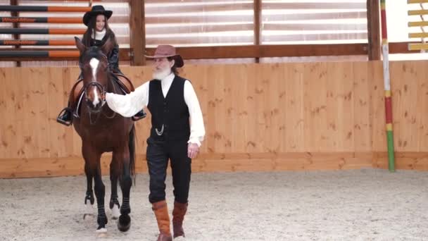 Senior man assisting granddaughter horseback riding in ranch — Stockvideo