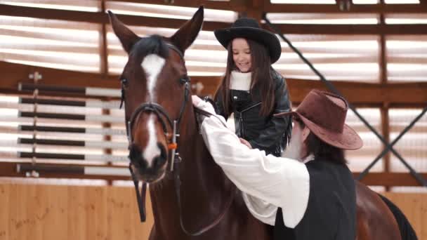 Senior man assisting granddaughter horseback riding in ranch — Wideo stockowe