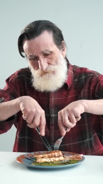 Senior man äter fiskbiff hemma — Stockvideo