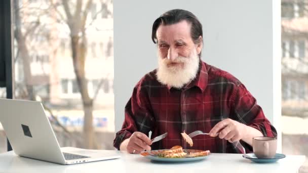 Senior man äter fiskbiff hemma — Stockvideo
