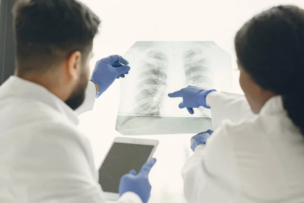 Médico y compañero de trabajo de pie y mirando rayos X en la clínica — Foto de Stock