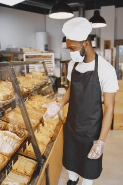 Maskeli yakışıklı Afro-Amerikan adam hamur işi sunuyor.