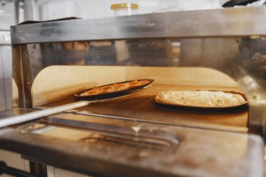 Afro-Amerikalı adam ticari mutfakta pizza pişiriyor.