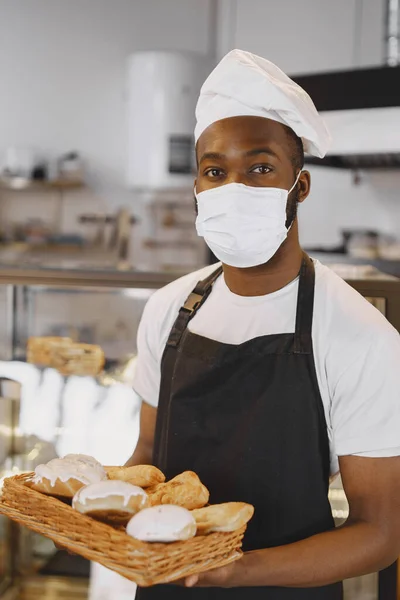 Afroamerikanischer Bäcker hält Tablett mit Brot in Bäckerei — Stockfoto