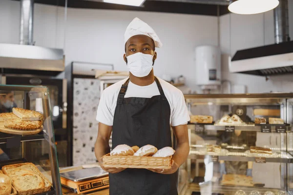 Афроамериканець тримає в пекарні тацю з хлібом. — стокове фото