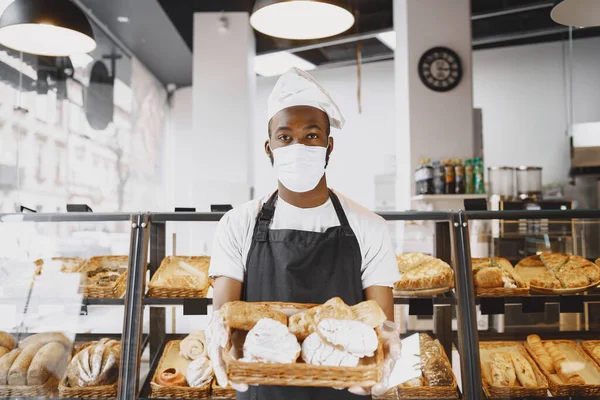 Panettiere afroamericano in possesso di vassoio di pane in panetteria — Foto Stock