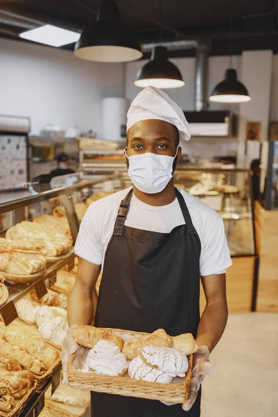 Афроамериканець тримає в пекарні тацю з хлібом. — стокове фото