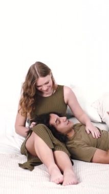 Beyaz yatakta çok ırklı çift kucaklaşması ve öpüşmesi.