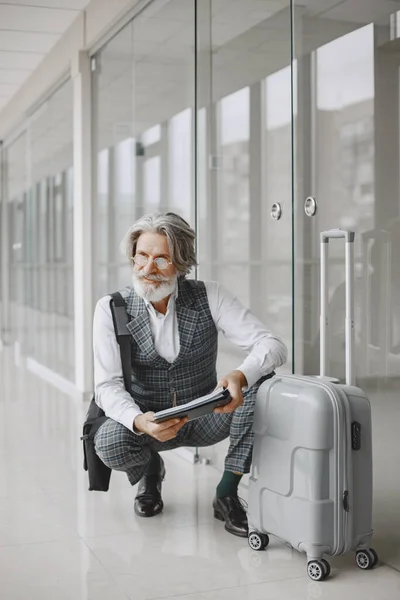 Senior Geschäftsmann mit Reisekoffer im Flughafen — Stockfoto
