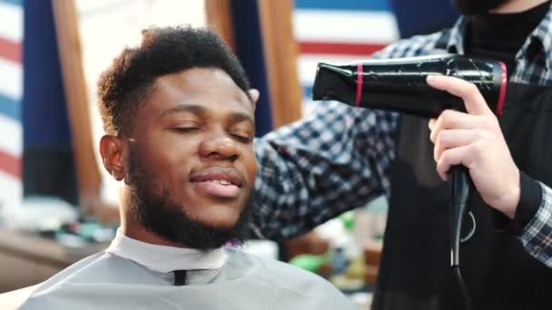 Peluquero usando secador de pelo mientras que hace corte de pelo al cliente masculino — Vídeo de stock