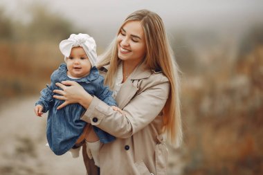 Anne ve kızı sonbahar tarlasında oynuyorlar.