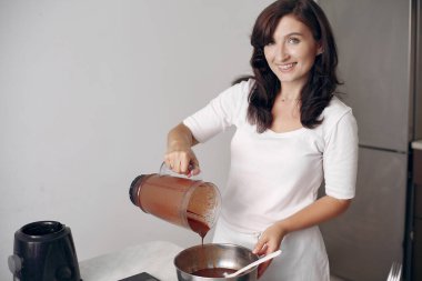 Beyaz elbiseli şef çikolatalı pasta hazırlıyor..