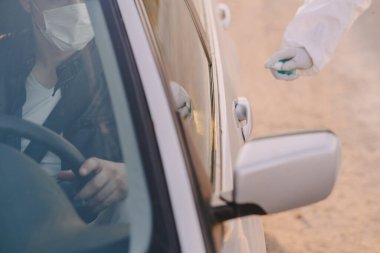 Koruyucu giysili biri arabayı dezenfekte ediyor.