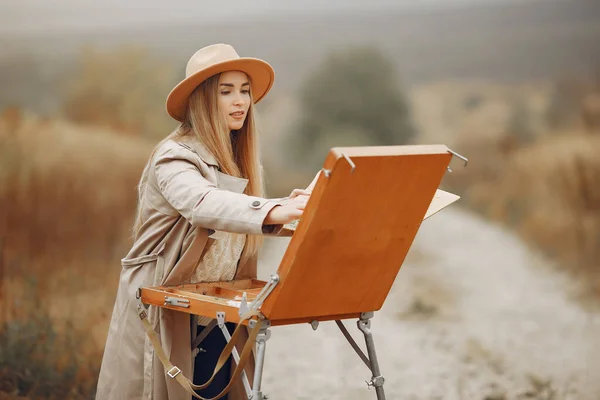Kobieta w brązowym płaszczu maluje na polu — Zdjęcie stockowe