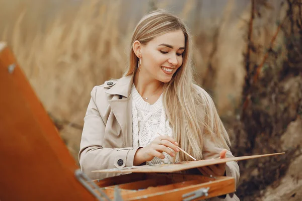 Kahverengi ceketli bir kadın tarlada resim yapıyor. — Stok fotoğraf