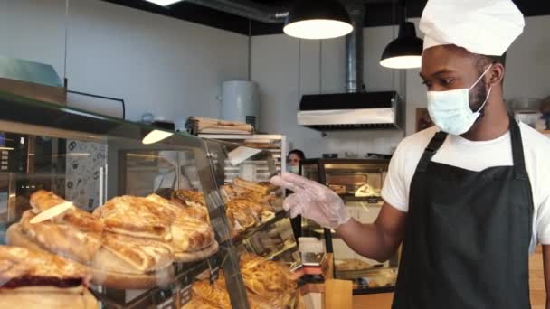 Homem afro-americano em máscara oferecendo pastelaria — Vídeo de Stock